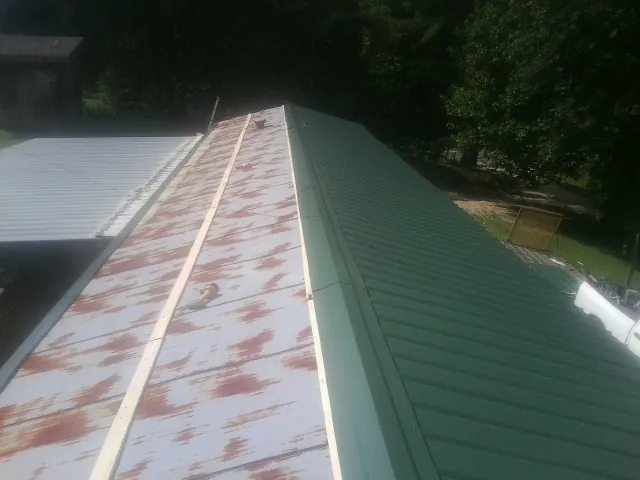Old rusted panels beside newly installed green metal roofing — Wind Damage Roof Repair by Roofing Brothers in Cowpens