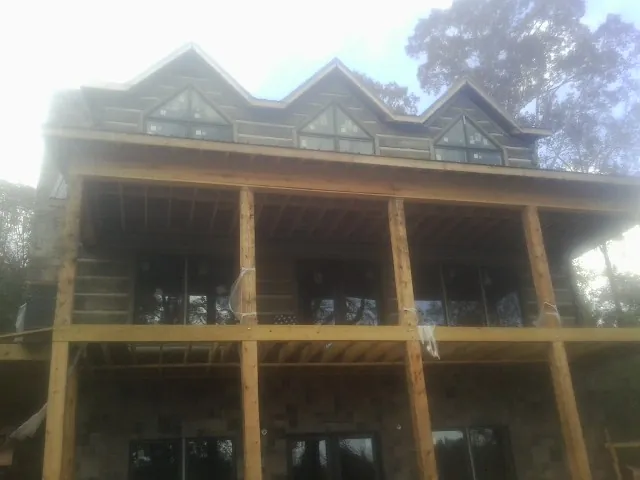 Dormers and porch framing on a large log home under construction — Roof Coating work by our crew in Cowpens
