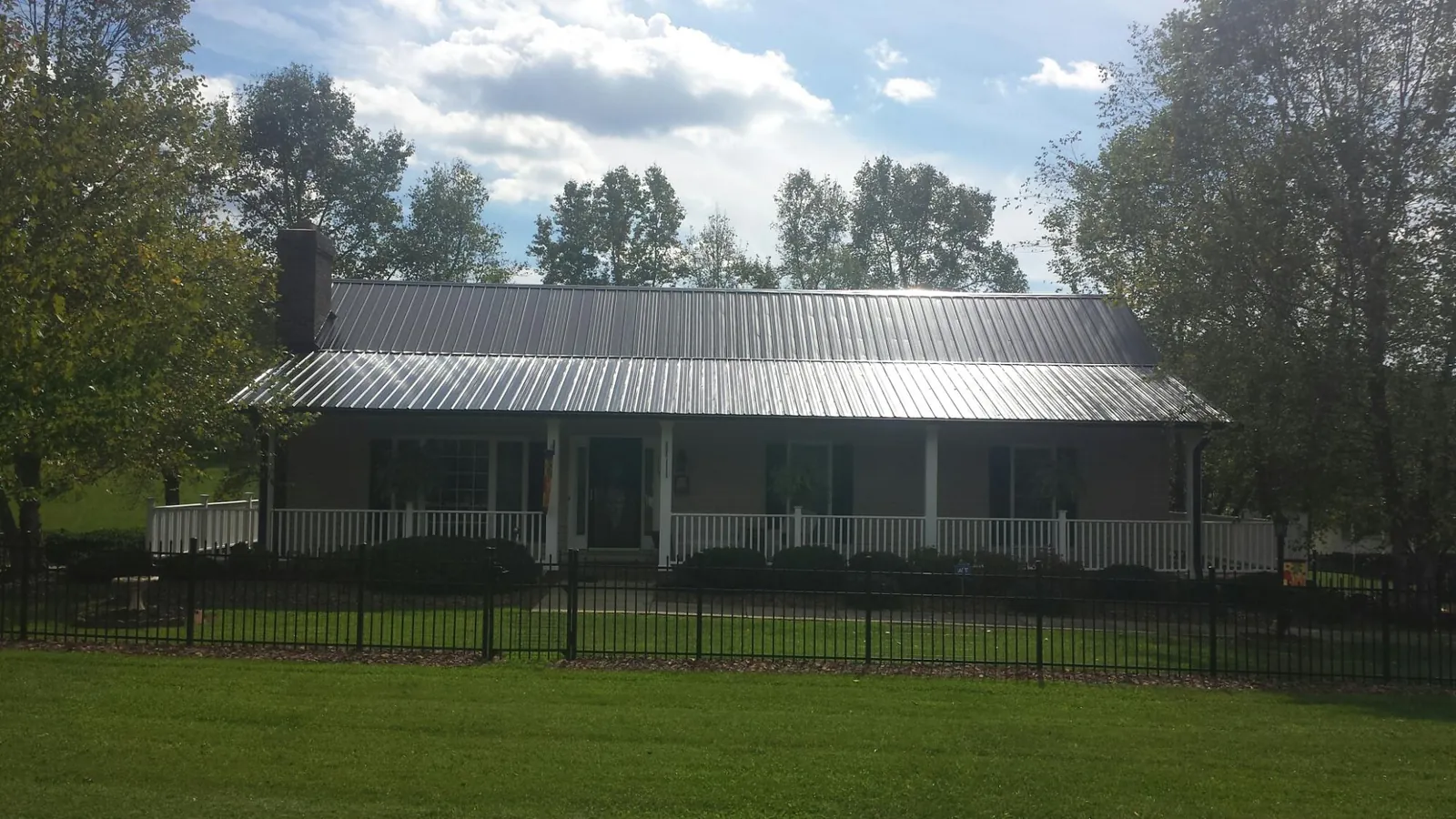 Gray metal roof on a brick ranch with a full width front porch — Gutter Guard Installation work by our crew in Cowpens