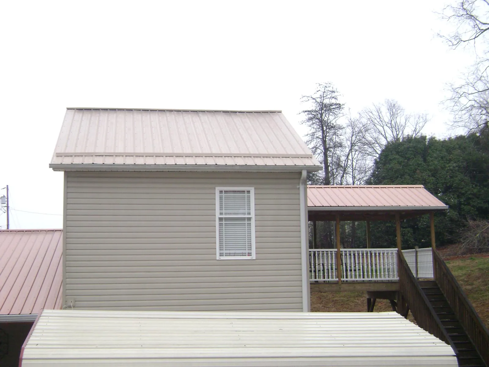 Tan metal roofs on a two story addition and attached porch, from a Roof Replacement job in Cowpens