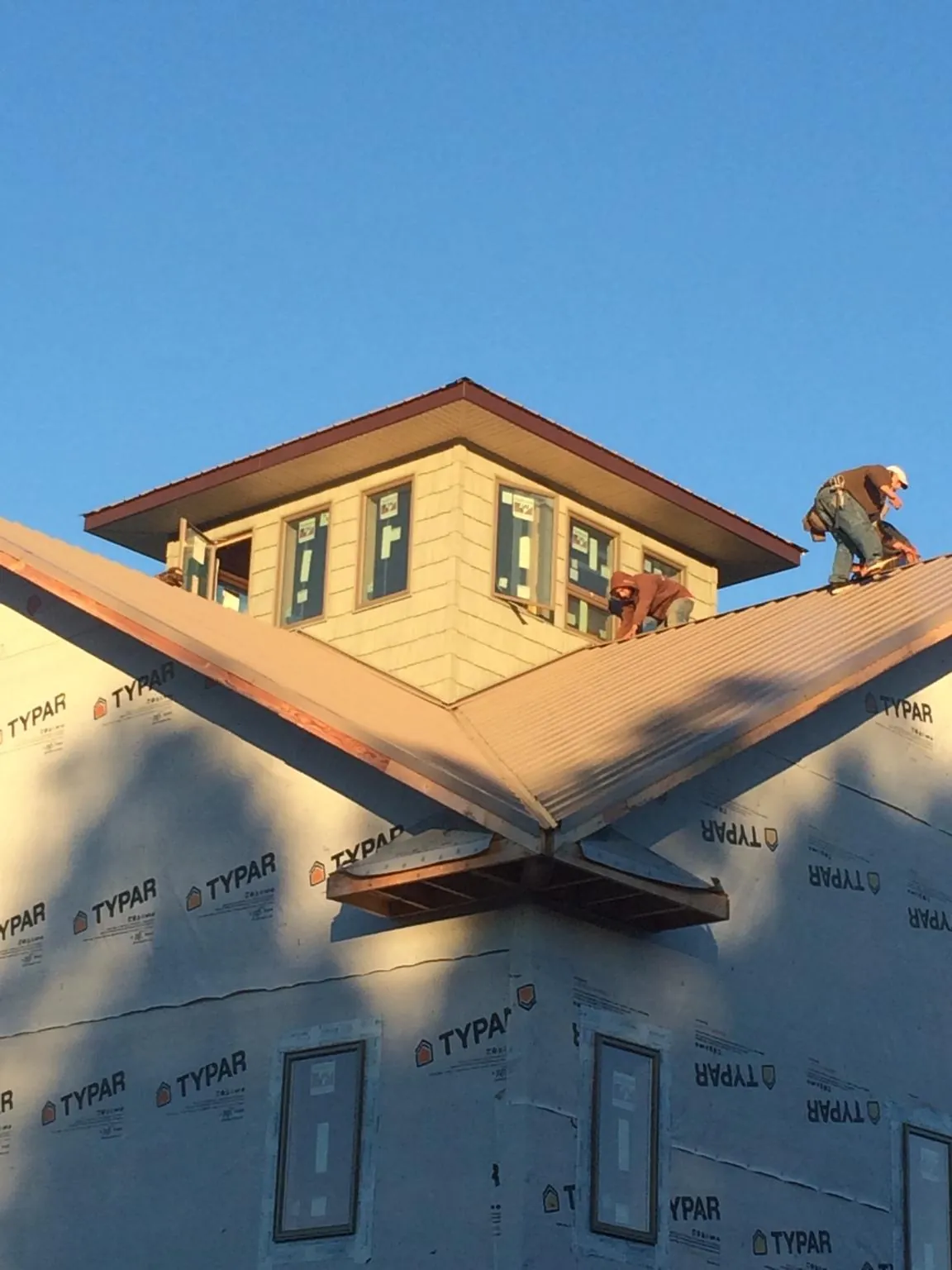 Roofers working around a rooftop cupola on a new metal roof at sunset — Roof Waterproofing in Cowpens by Roofing Brothers